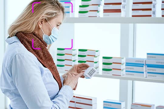 farmacista-femminile-in-una-maschera-protettiva-in-piedi-vicino-a-una-vetrina-della-farmacia-foto-con-copia-spazio-min